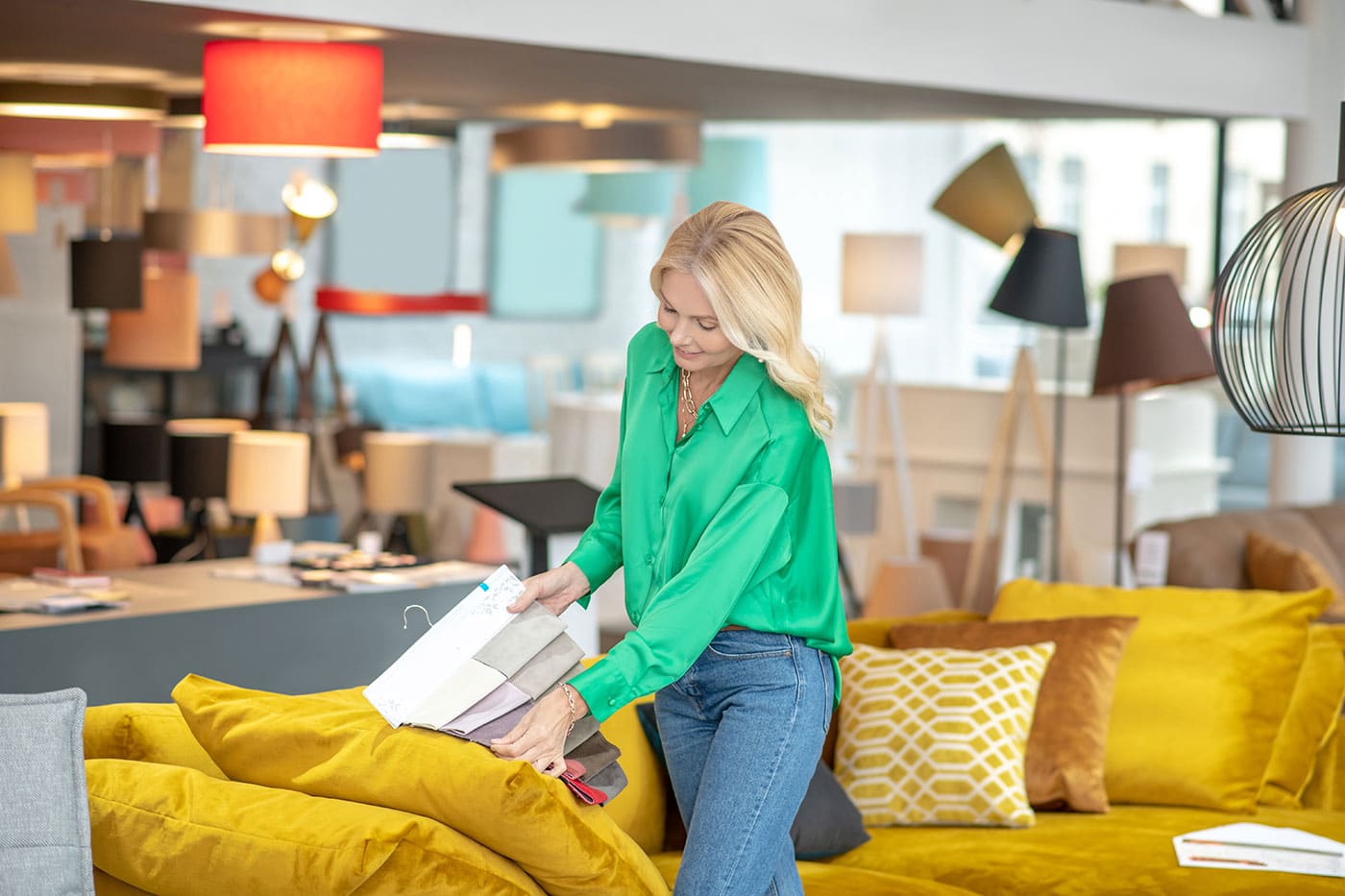 En dame i grøn trøje der kigger på en ny sofa i en buik