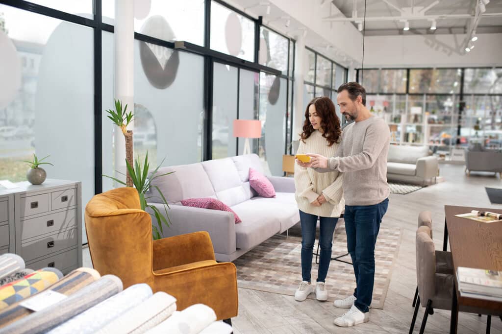 en mand og en dame der shopper efter en ny sofa i en butik